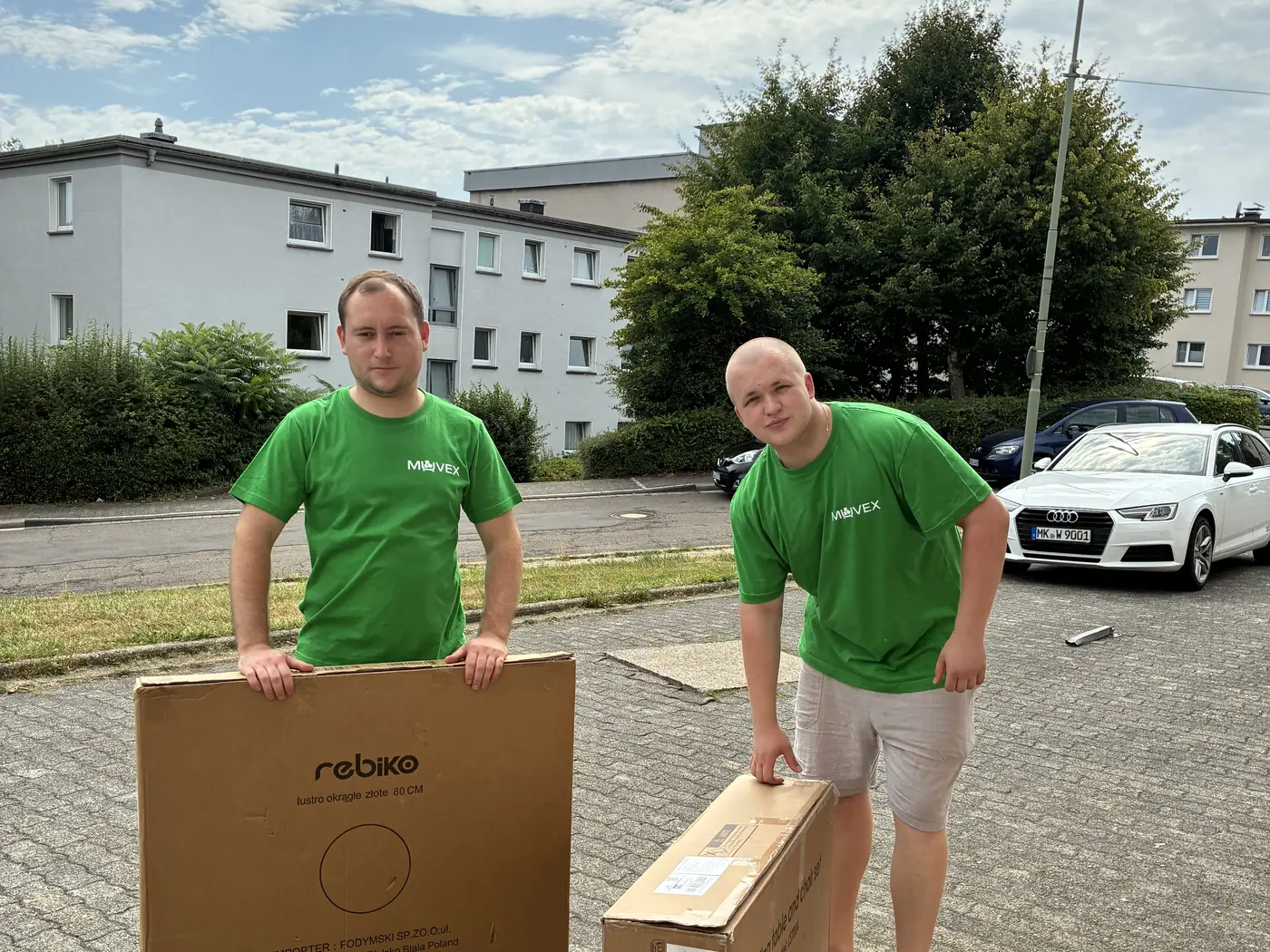 Muvex-Team mit Umzugskartons vor einem Wohnhaus — Umzug in Essen