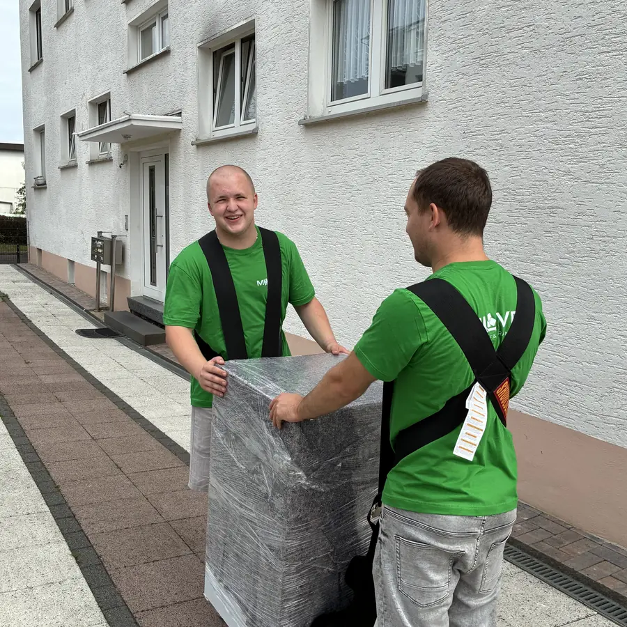 Verpacktes Möbelstück wird mit Tragegurten aus dem Haus getragen