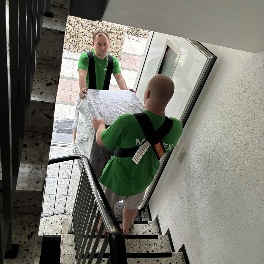 Ein Spiegel wird geschützt durch das Treppenhaus getragen