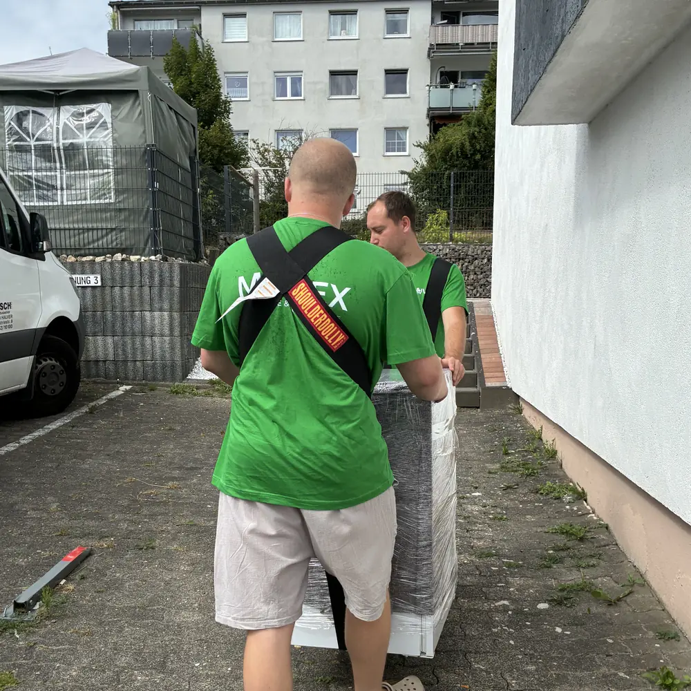 Muvex-Team trägt ein verpacktes Möbelstück beim Privatumzug aus dem Haus