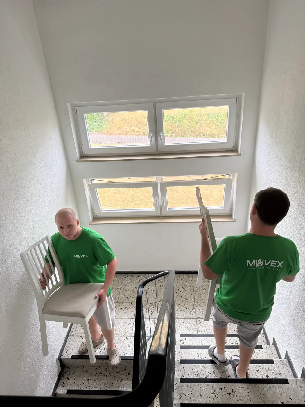 Muvex-Mitarbeiter trägt einen Stuhl die Treppe hinunter